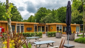 Un espace d’accueil doté d’une façade en bois, de sièges extérieurs et d’un parasol.