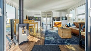 A modern living room with a fireplace, a dining area, and a kitchen. - Floating house with fireplace on the lagoon (Ribnitz-Damgarten)
