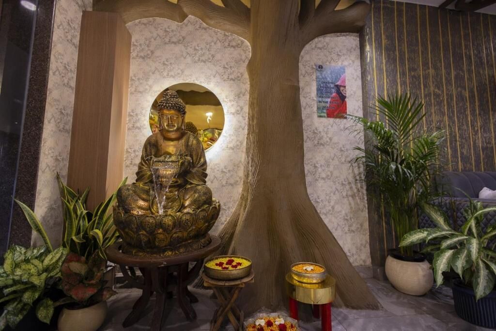 A Buddha statue in a niche, surrounded by potted plants and a small table with offerings.