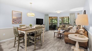 A living room with a dining table, chairs, a sofa, a TV, and a lamp. - Kingston Plantation-Sleeps 6-2bed/2bath-Full Kitchen-Laundry-Lake View (Myrtle Beach)
