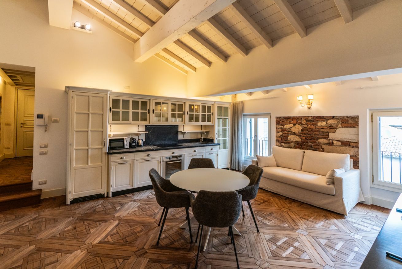 A spacious living area with a dining table, white cabinets, and a stone accent wall.