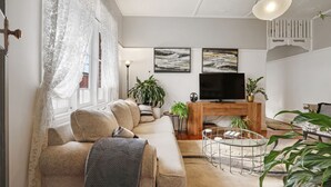 Ett modernt vardagsrum med en soffa, ett soffbord, en tv och dekorativa växter.
