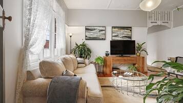 A modern living room with a sofa, a coffee table, a TV, and decorative plants.