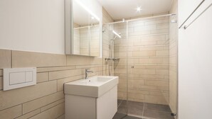 Une salle de bain moderne avec un lavabo blanc, un miroir et une douche.