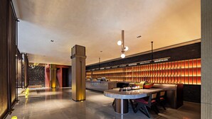 A modern lobby with a reception desk, seating area, and a large wall of illuminated panels. - Sail Hotel (Chongqing)