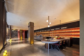 A modern lobby with a reception desk, seating area, and a large wall of illuminated panels. - Sail Hotel (Chongqing)