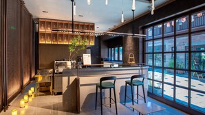 A modern bar area with a counter, stools, and large windows. - Sail Hotel (Chongqing)