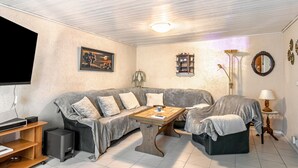 Ein gemütliches Wohnzimmer mit Sofa, Couchtisch, Fernseher und Lampe.