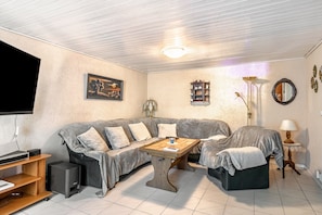 Un salon confortable avec un canapé, une table basse, un téléviseur et une lampe.