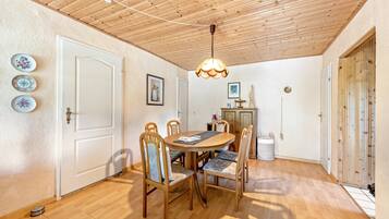 A dining area with a wooden table, chairs, and a ceiling light fixture.