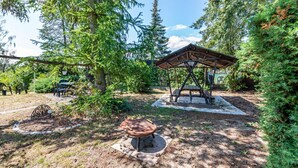 Ein rustikaler Außenbereich mit einem Holzpavillon, einem Grill und Picknicktischen.