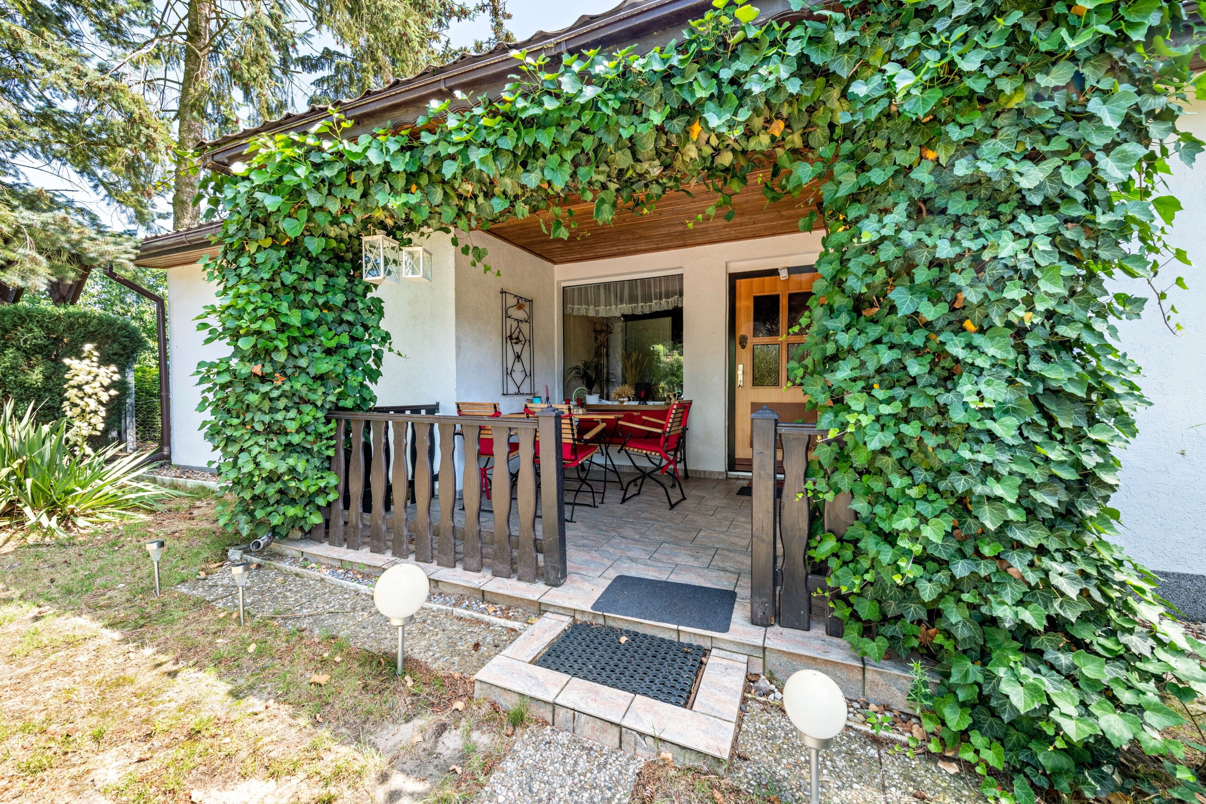 A house with a covered patio area, a wooden fence, and a garden.