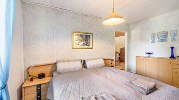 A bedroom with a bed, bedside table, lamp, and a painting on the wall.