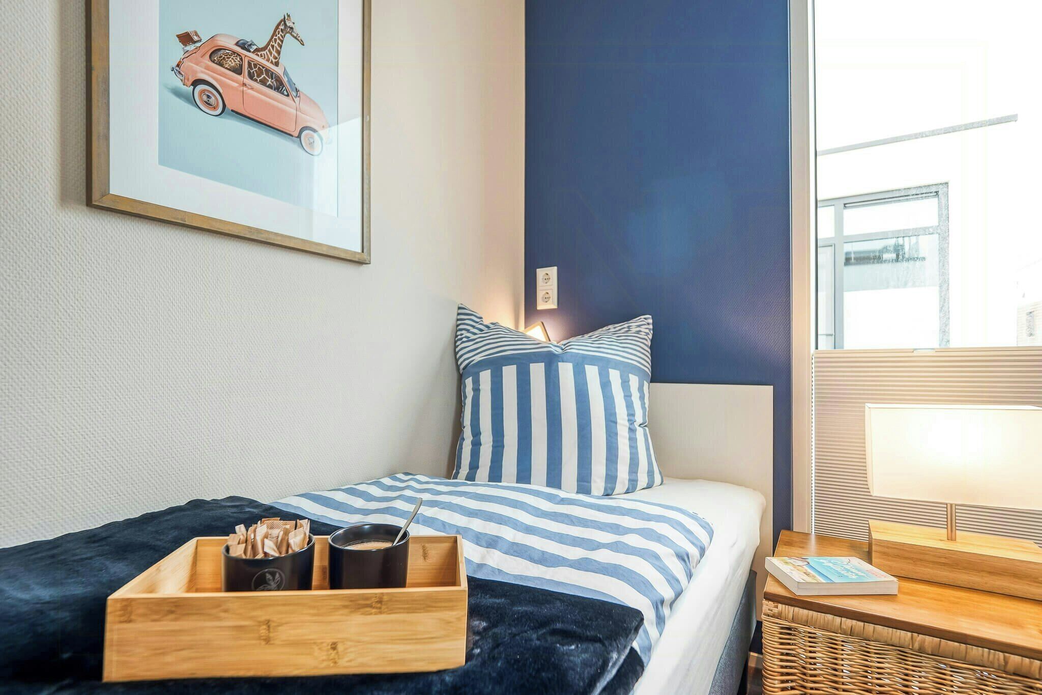 Une chambre d’hôtel avec un lit, des oreillers, une table de chevet avec une lampe, un tableau encadré au mur et une fenêtre.