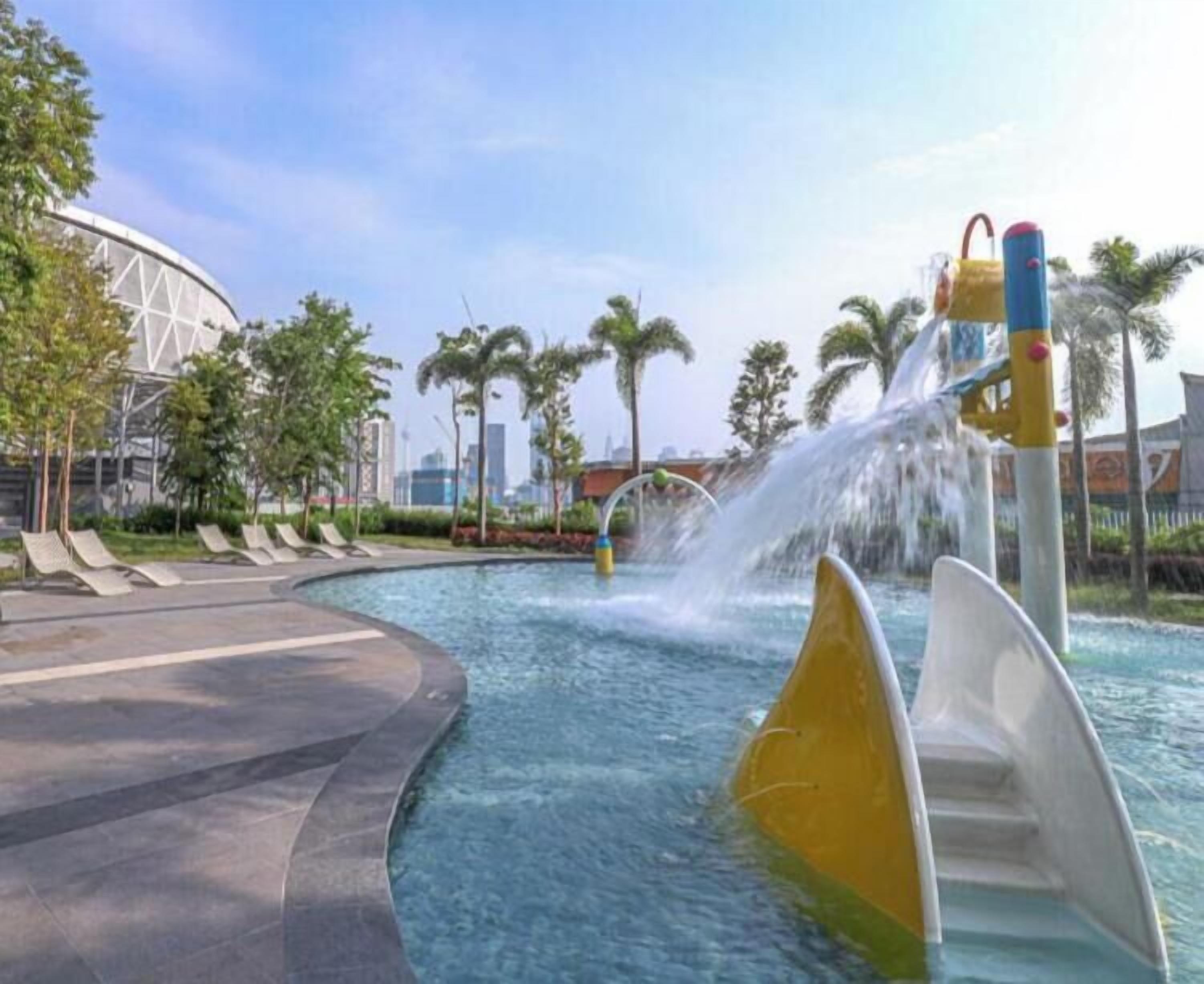A water feature with a slide, a curved pool, and a modern building in the background.