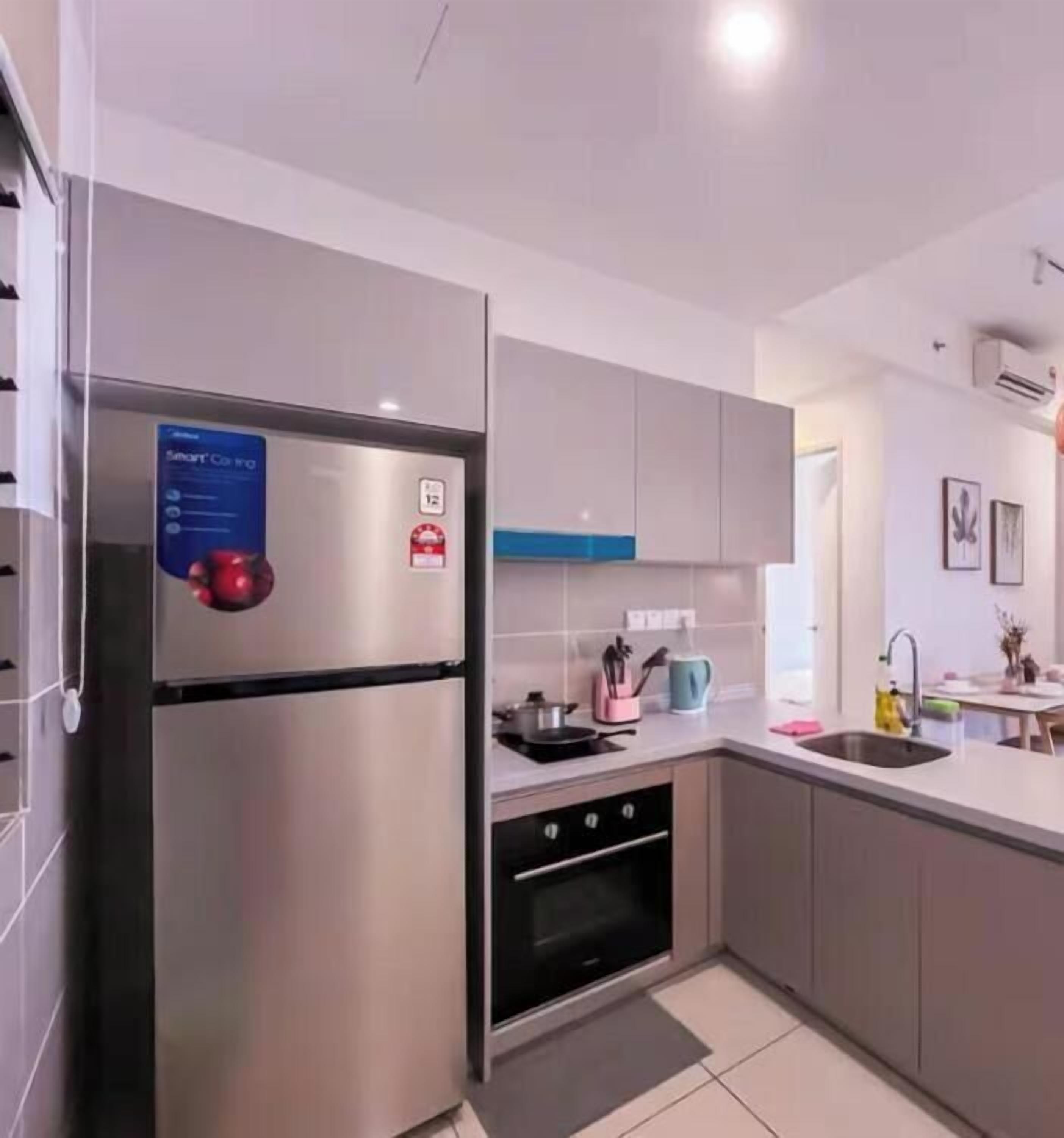 A modern kitchen with a stainless steel refrigerator, a built-in oven, and a sink.
