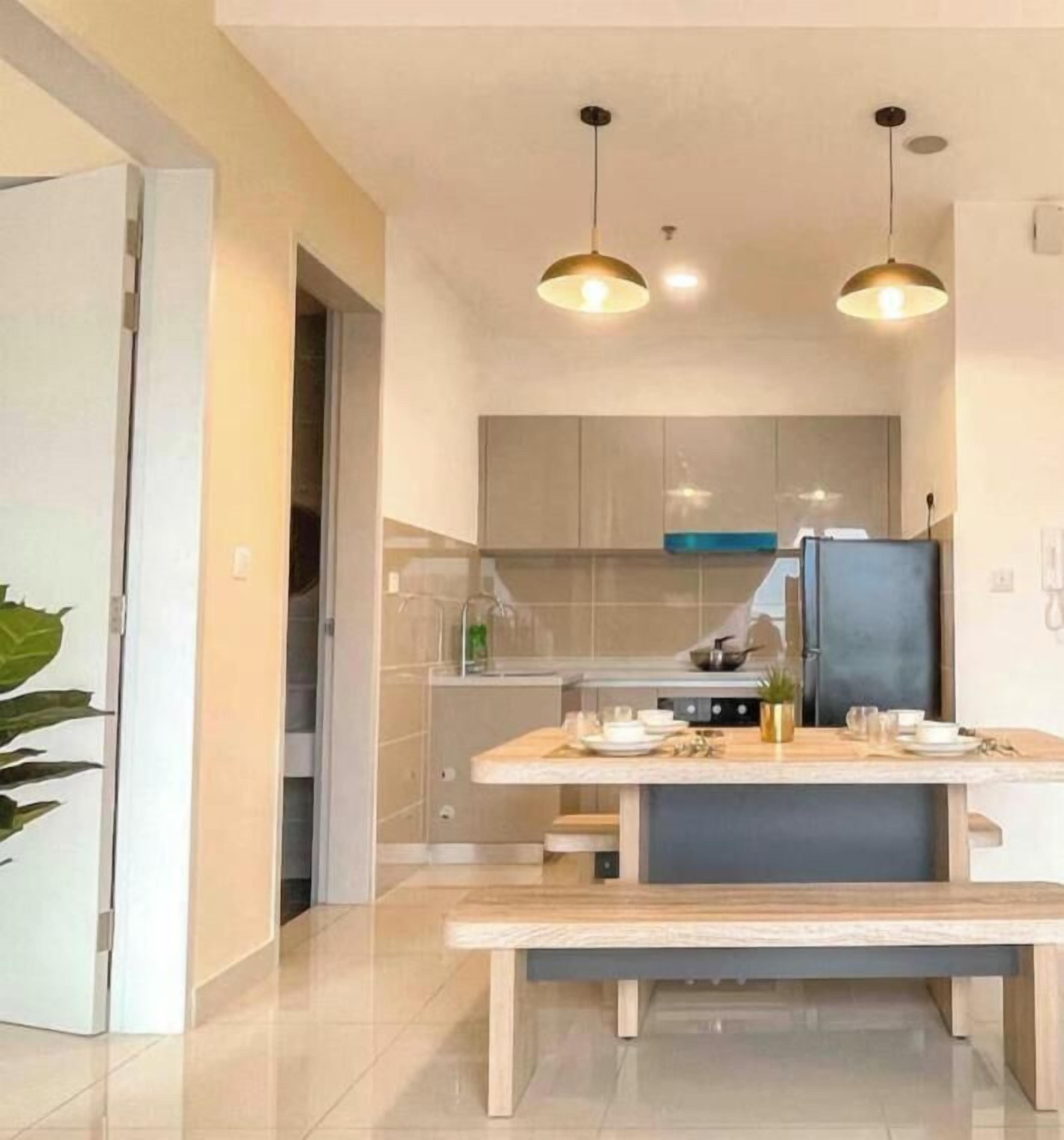 A modern kitchen with a central island, pendant lighting, and a bench.