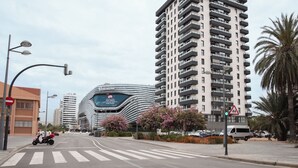 A city street with modern buildings, a pedestrian crossing, and a traffic sign.