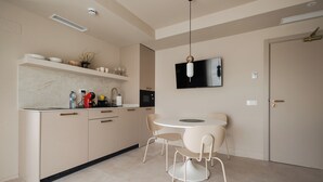 A modern kitchen with a dining area, a flat-screen TV, and a door with a handle.