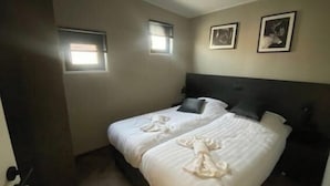 A bedroom with a bed, two windows, and two framed pictures on the wall. - Holiday Home in Kampen With Terrace (Kampen)