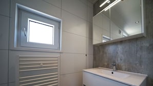 A bathroom with a window, a radiator, a sink, and a mirror. - Holiday Home in Kampen With Terrace (Kampen)