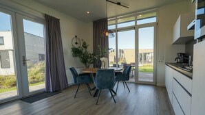 A modern kitchen with a dining area, large windows, and a view of the outdoors. - Holiday Home in Hindeloopen With Wi-fi (Hindeloopen)