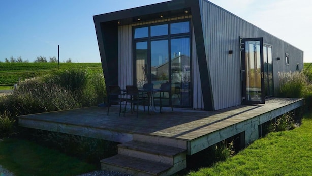 A modern house with a large glass door, a deck, and a view of the surrounding landscape. - Holiday Home in Hindeloopen With Wi-fi (Hindeloopen)