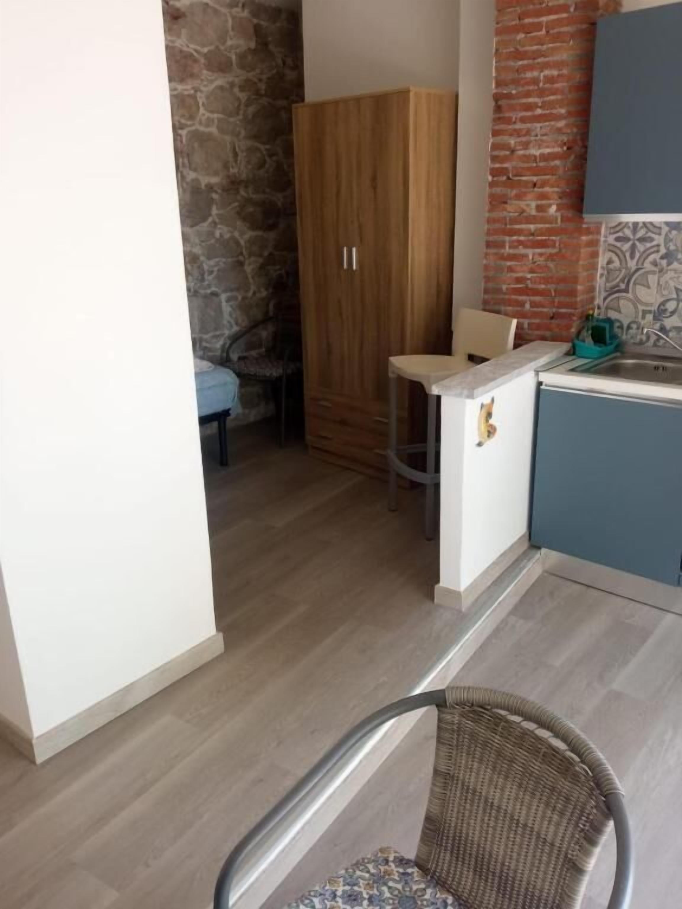 Une cuisine avec des meubles en bois, un plan de travail bleu et un mur en pierre.