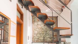 Una escalera de caracol con escalones de madera y barandillas de metal, una pared de piedra y un piso de baldosas.