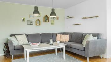 Una sala de estar moderna con un sofá seccional gris, una mesa de centro blanca y dos lámparas colgantes.