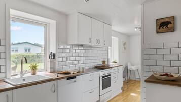 Una cocina moderna con armarios blancos, encimera de madera y vistas al exterior.