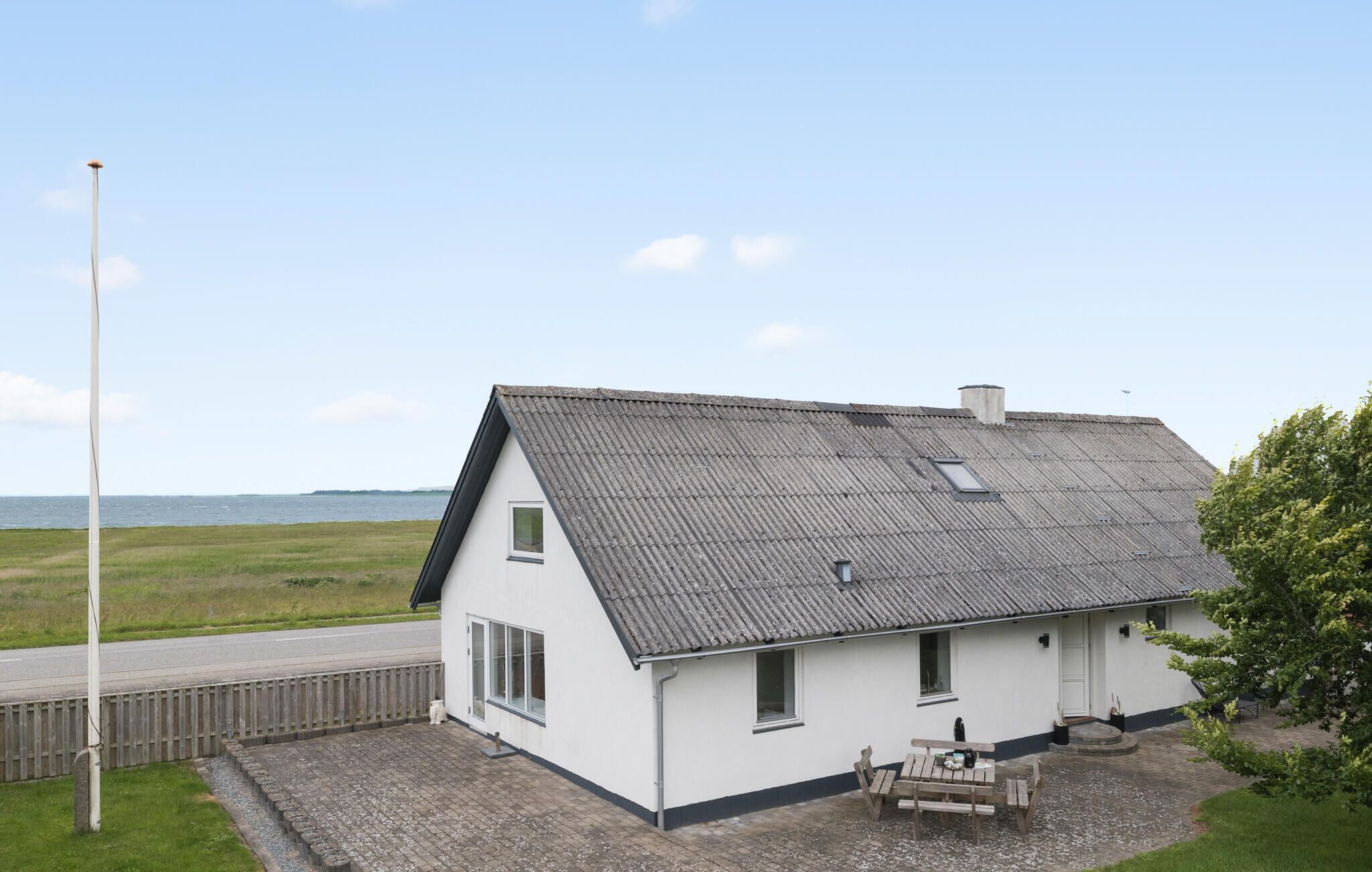 Una casa blanca con techo gris, un pequeño porche y vistas al mar.