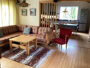 A cozy living room with a wooden sofa, a red chair, a wooden coffee table, and a patterned rug. - 4 Star Holiday Home in Heberg (Heberg)