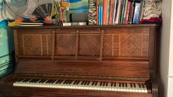 Un piano sur lequel sont posés un ventilateur et des livres.