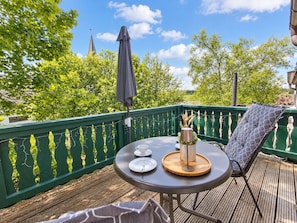 Une terrasse avec une table ronde, des chaises et une petite plante en pot.