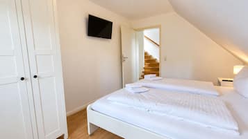 Ein Schlafzimmer mit einem Bett, einem Kleiderschrank, einem Fernseher und einer Treppe.