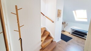 A staircase with wooden steps and handrails, a white wall, a skylight, and a small shelf with a vase. - FeWo Merle Altastenberg – Nature & Active Holidays (Winterberg)