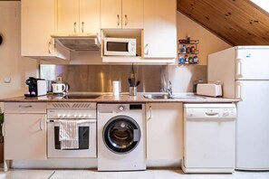 A compact kitchen with a microwave, oven, dishwasher, and a sink. - Terrace, bright, and centrally located (Madrid)