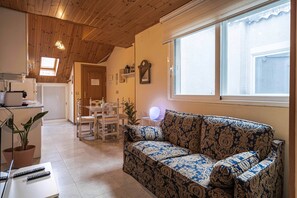 A cozy living room with a patterned sofa, a dining table with chairs, a kitchen area with a refrigerator, and a large window providing natural light. - Terrace, bright, and centrally located (Madrid)