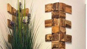 Eine Wand mit vertikaler Holzstruktur und einer großen, goldenen Vase mit Grünpflanzen.