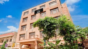 Un hotel de varios pisos con fachada de ladrillo, un letrero en la parte superior y una entrada protegida por una reja.