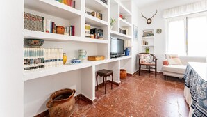 Ein Wohnzimmer mit Fernseher, Bücherregalen, einer Couch und einem dekorativen Wandstück mit Geweihen.