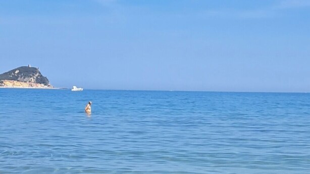 A beach with clear water, a sandy shore, and a distant island. - Ligurian Oasis (Pietra Ligure)