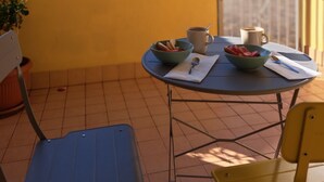 A round table with a bowl of fruit, a cup of coffee, and a spoon on a yellow wall. - Ligurian Oasis (Pietra Ligure)