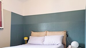 A bedroom with a bed, bedside table, lamp, and alarm clock. - Ligurian Oasis (Pietra Ligure)