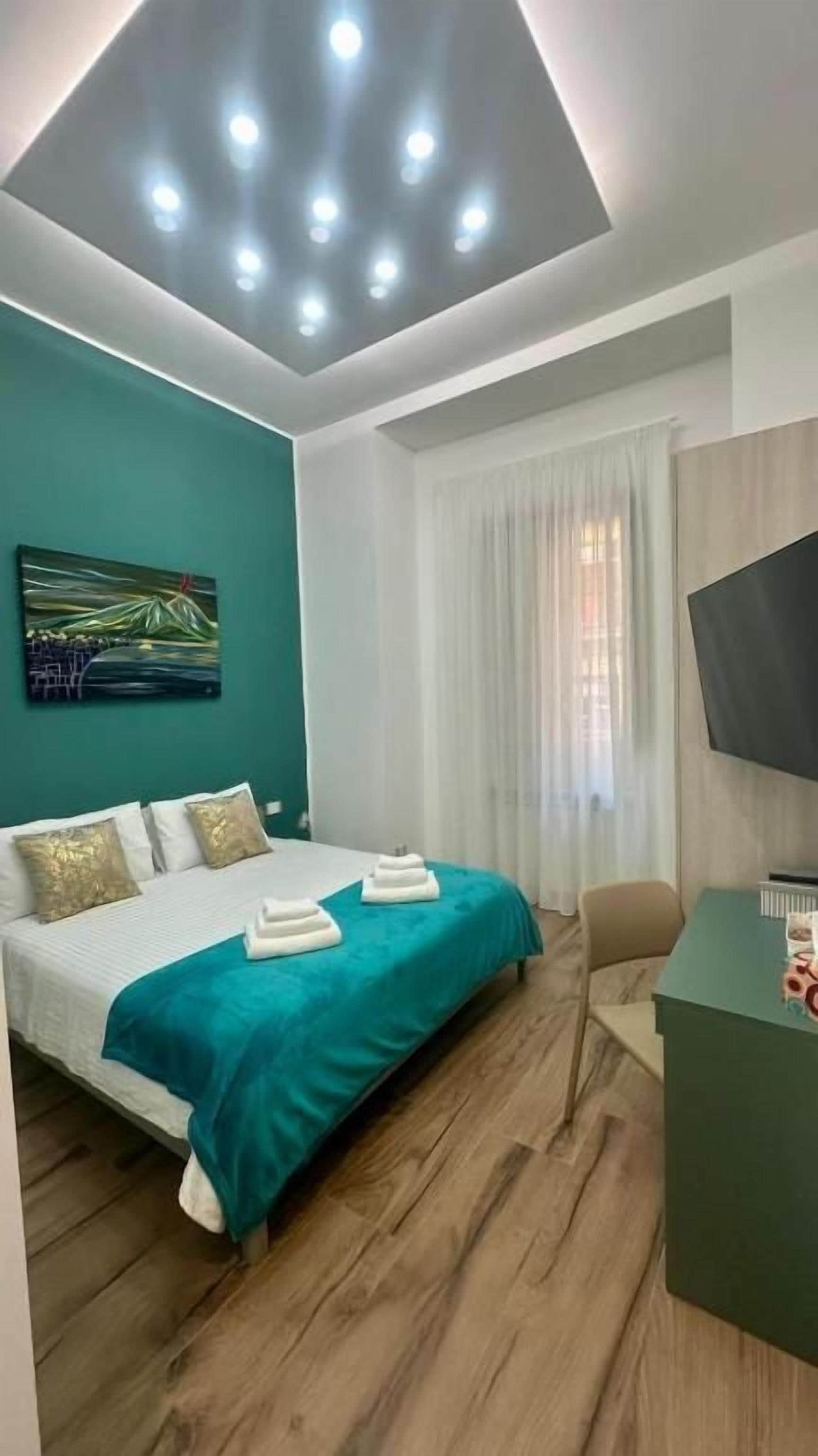 Una camera d'albergo con un letto, una scrivania, una televisione e un quadro appeso al muro.