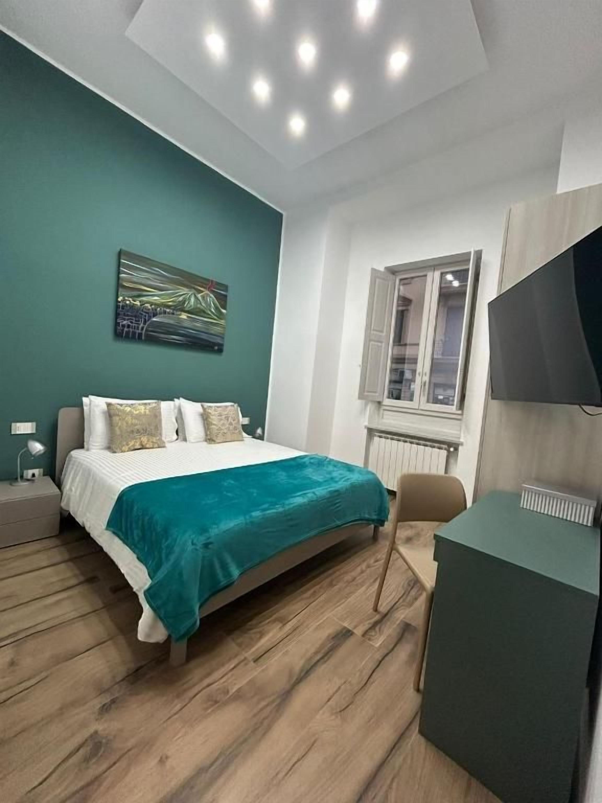 Una camera da letto con un letto, una scrivania, una sedia, una finestra e un quadro appeso al muro.