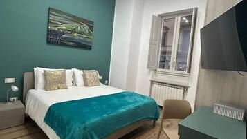 Una camera da letto con un letto, una scrivania, una sedia, una finestra e un quadro appeso al muro.