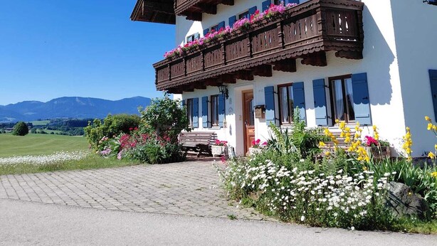 A two-story building with wooden balconies, a white facade, and a mountain view. - Vacation rental, 45 square meters, 2nd floor, 1 separate bedroom (Bad Endorf)