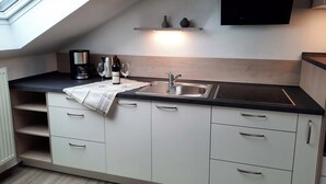 A modern kitchen with a skylight, a built-in sink, and a wine bottle. - Vacation rental, 45 square meters, 2nd floor, 1 separate bedroom (Bad Endorf)